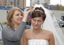Свидетельница подправляет свадебную причёску, макияж, платье.